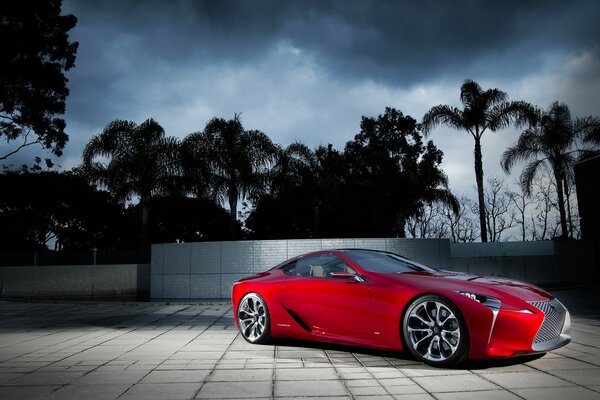 Night. Bright red car on a background of palm trees