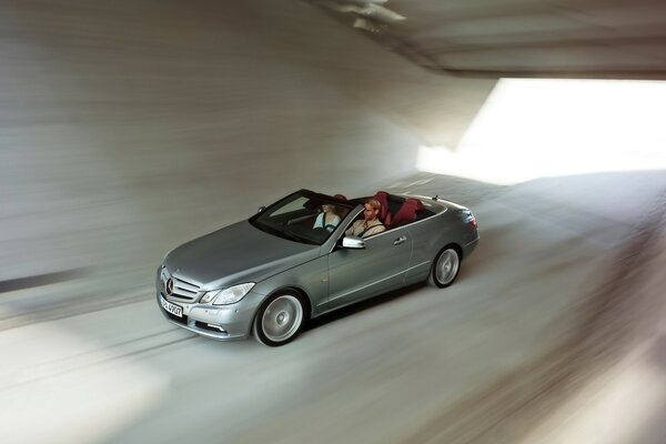 A silver-colored car drives along an underground roadway