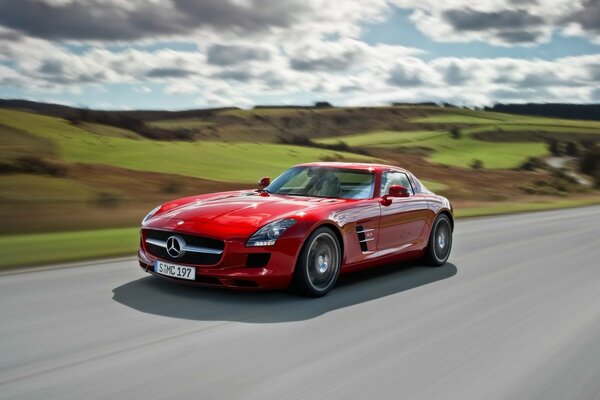 A bright red car is driving at speed on a perfect road