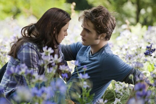 A guy and a girl are sitting in a clearing in flowers