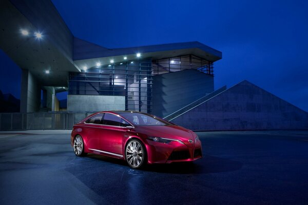 Voiture rouge vif sur le fond de la maison pendant la nuit