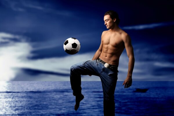 A guy on the shore playing with a ball with a bare torso