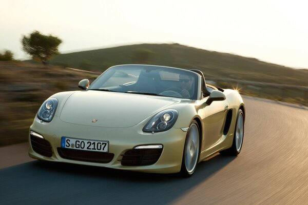 A man in a beige convertible rides with the breeze