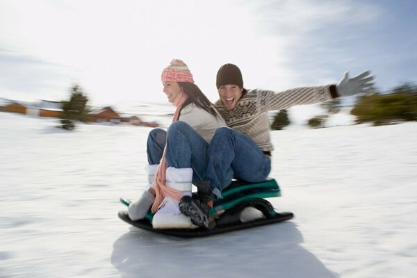 Guy girl couple sledge down the mountain snow day sun