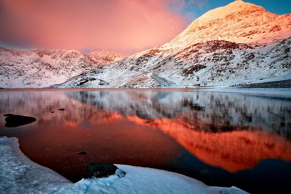 Magníficas montanhas cobertas de neve e seu reflexo na água