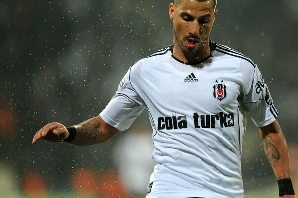 Futbolista bajo la lluvia con uniforme blanco