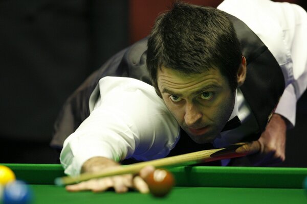 A snooker player prepares to score a ball into the pocket