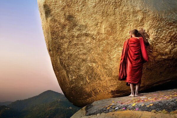 A sadly sad figure against the background of a large stone