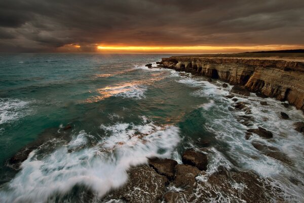 Wellen schlagen gegen Steine. Sonnenuntergang am Meer Hintergrund