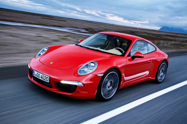 A red Porsche rushes across the asphalt