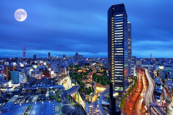 一座宏伟的摩天大楼在城市上空，以夜空为背景，满月升起