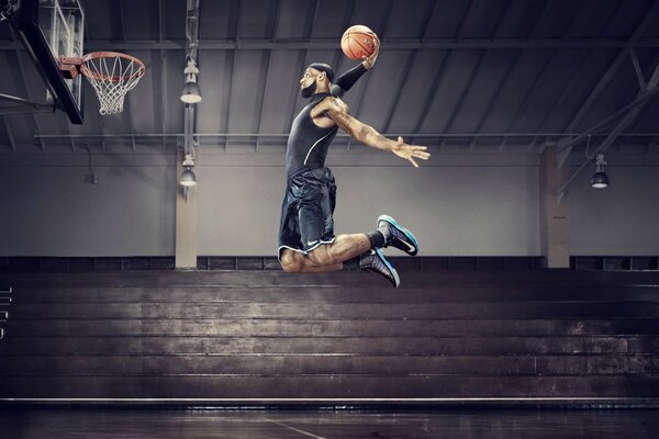 Ein Basketballspieler wirft den Ball im Sprung in den Korb