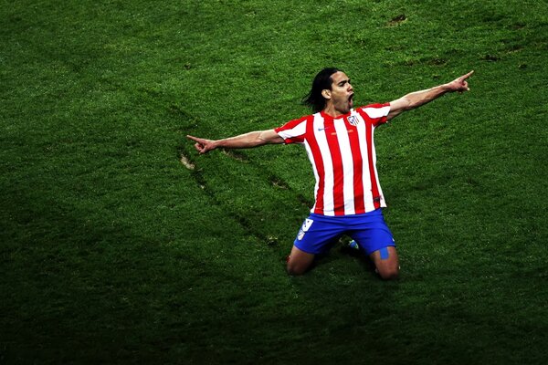 The soccer player who scored the goal in a red and blue uniform rejoices on his knees