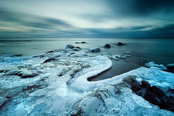 Paesaggio di pietre congelate nel ghiaccio. Tramonto sul mare d inverno