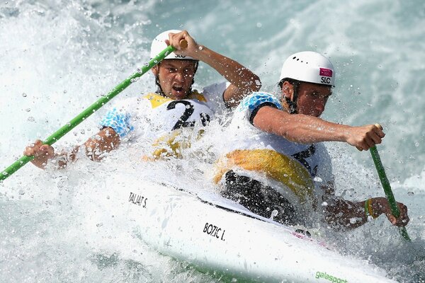 A kayak with two rowers dissecting a seething stream of water