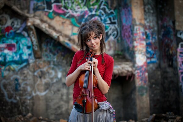 Violinist in red on the background of a wall with graffiti