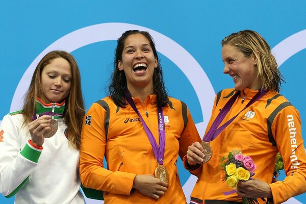 Três campeãs olímpicas com medalhas na cerimônia de premiação