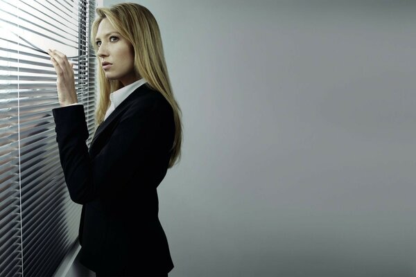 A girl alone in front of a window with blinds