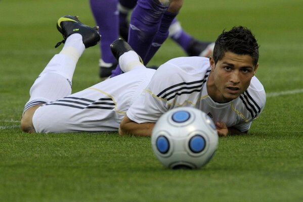 Joueur de football est tombé et regarde la balle