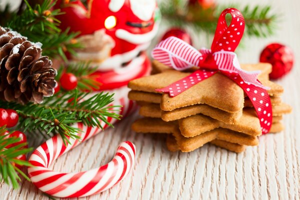 Biscotti allo zenzero a forma di stelle che giacciono accanto ai rami dell albero di Natale e al cono