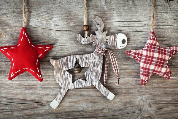 Un cerf en bois avec un arc et une paire de pendentifs étoiles de Noël cousus en tissu