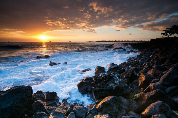 Rocky beach, sunset, waves. The foaming sea