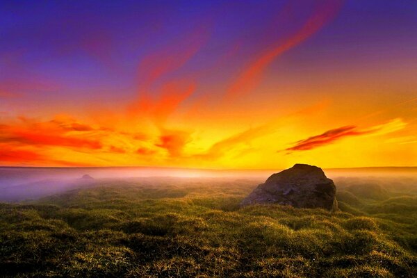 Nebeliger Sonnenuntergang wird von Felsbrocken begrüßt