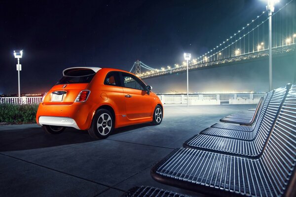 Voiture orange garée sur le front de mer avec vue sur le pont