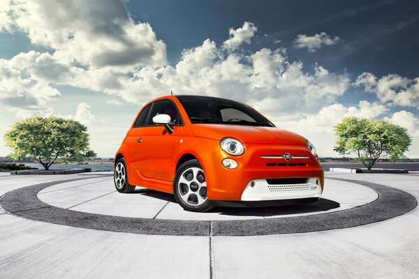 Orange small Fiat in the center of the circle against a cloudy sky