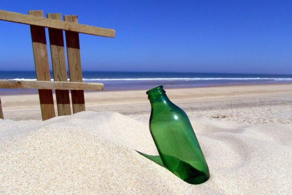 Bottiglia verde su sfondo di sabbia bianca