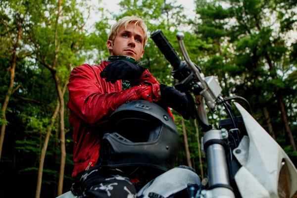 Homme assis sur une moto avec un casque dans les mains