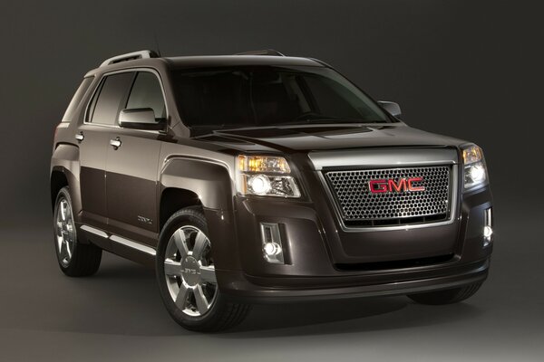 A Gmc car stands in front of a gray background