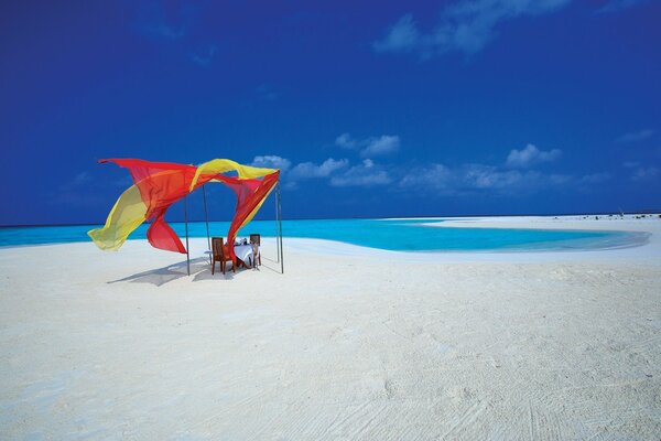 सफेद रेत और नीले समुद्र के साथ एक निर्जन समुद्र तट पर रोमांटिक टेबल