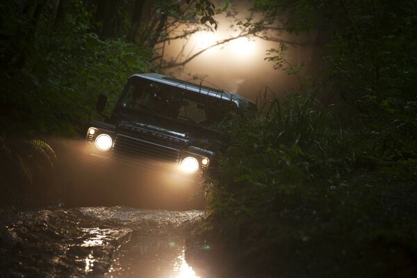 An SUV car lights its way in the forest