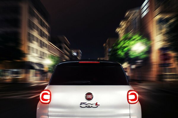 A white Fiat driving fast through the city