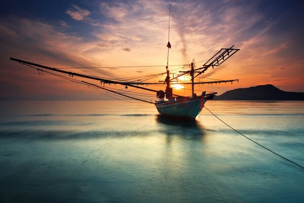 The ocean with a boat penetrates the red sunset