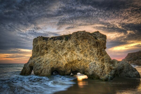 Sea waves break on the rocks at sunset