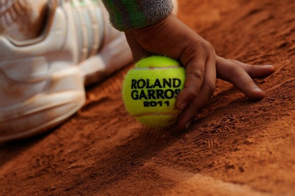 Mano de bebé. sosteniendo una pelota de tenis del torneo Roland Garros 2011