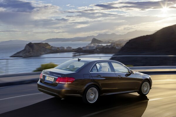 Mercedes Benz fährt entlang der Berge und des Wassers