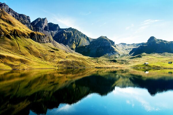 Felsige Berge mit grünem Gras am Wasser