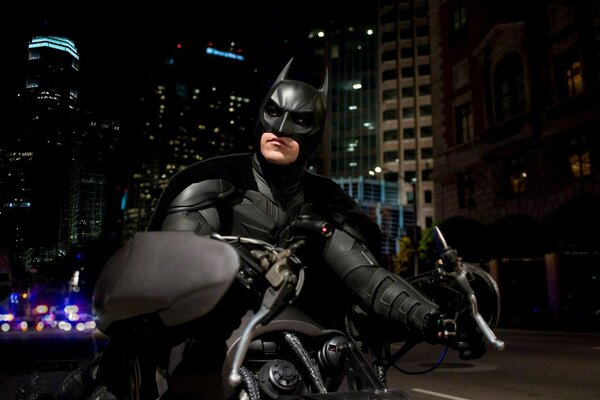 Batman auf seinem schwarzen Motorrad vor dem Hintergrund der nächtlichen Stadt