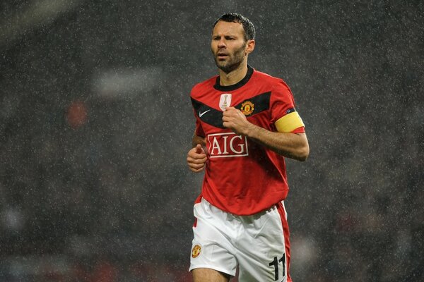 A football player in a red T-shirt running in the rain