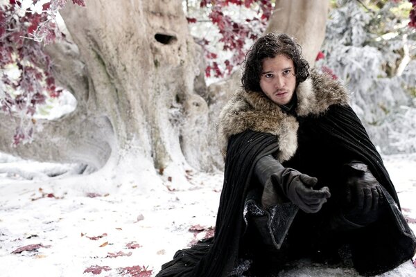 Jon Snow is sitting in the snow