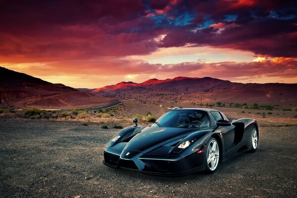 Coche de carreras de moda negro en el desierto al atardecer