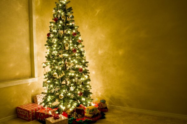 A Christmas tree in the light of lights storing boxes with gifts under it