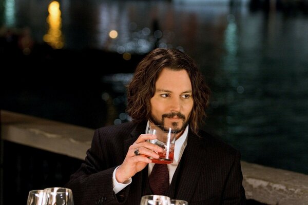 Schauspieler am Wasser mit einem Glas in der Hand