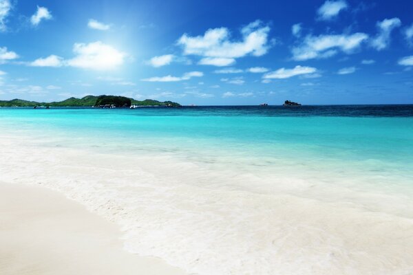 Sonniger Himmel über weißem Strand und türkisfarbenem Wasser