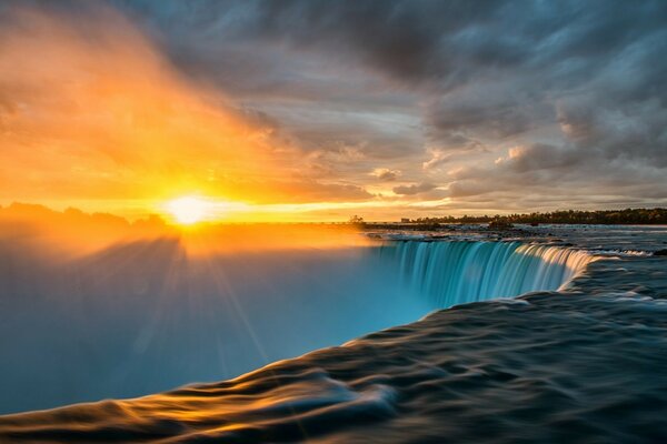 Nebliger Wasserfall bei Sonnenuntergang mit Wolken