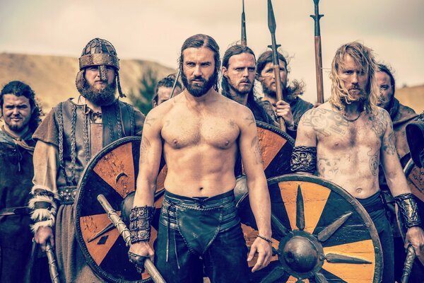 Long-haired Viking guys hold shields and pikes