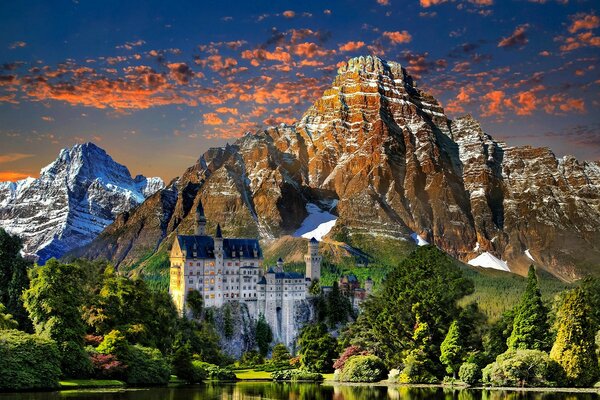 Paisagem montanhosa com castelo e árvores com nuvens vermelhas no céu